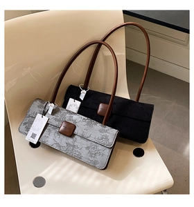 Détail de sacs baguette en jacquard fleuri et cuir noir posés sur une chaise élégante
