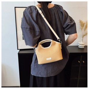Détail de la texture en paille tressée et poignée en cuir blanc du sac bandoulière