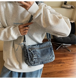 Detail of blue denim crossbody bag with multiple silver zippers and adjustable strap
