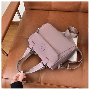 Detailed side view of mauve nylon handbag with DAIOU logo on dark leather surface