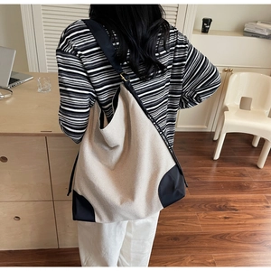 Detail of minimalist canvas tote bag showing black leather trim and adjustable strap