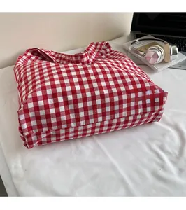 Macro shot of durable red and white checkered canvas tote bag with laptop and books