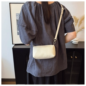 Gros plan du sac à bandoulière en cuir crème avec crochets dorés sur un mannequin