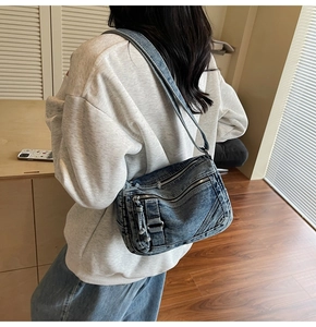 Macro shot of retro blue denim crossbody bag with metal zippers on the shoulder strap