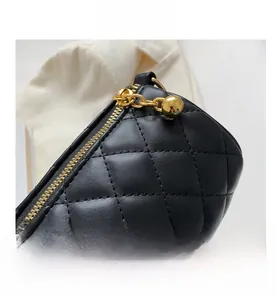 Détail d'un sac cylindre en cuir noir matelassé avec fermeture éclair dorée et pendentif