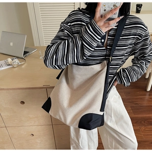 Minimalist beige canvas tote bag with black base held by model in casual lifestyle setting