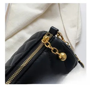 Détail de la texture en cuir noir matelassé avec fermeture éclair dorée et boule de chaîne