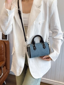 Blue denim mini Boston bag with black leather straps worn by model in a white blazer