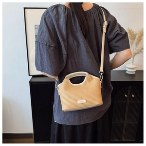 Détail du sac cabas en paille tissée avec poignée en cuir et bandoulière réglable sur le mannequin