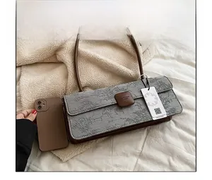 Sac sous le bras en jacquard gris avec bandoulière marron comparé à un téléphone pour la taille