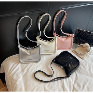 Detailed display of assorted glossy pleated crossbody bags in silver, white, pink and black