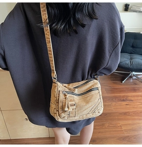 Detail of khaki washed canvas crossbody bag with multiple zippers worn by model