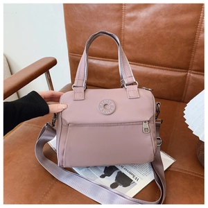 Detail of pink nylon crossbody bag with adjustable wide strap and round logo on a chair