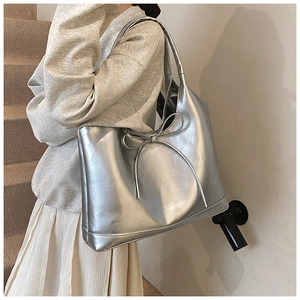 Detail of silver metallic tote bag featuring a bow decoration and smooth finish