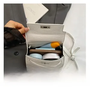 Detail showing internal capacity of white crocodile pattern mini bag with metal lock