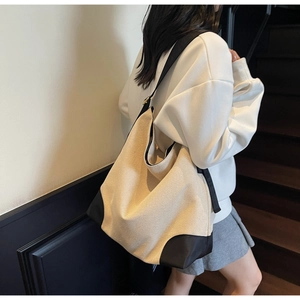 Detail view of a minimalist canvas tote bag with black reinforced corners and wide shoulder strap
