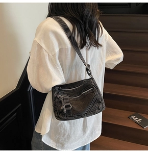 Detailed view of the dark grey washed denim crossbody bag featuring multiple zipper pockets