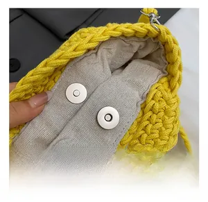 Detail view of yellow knit bucket bag featuring a gray lining and silver magnetic closures