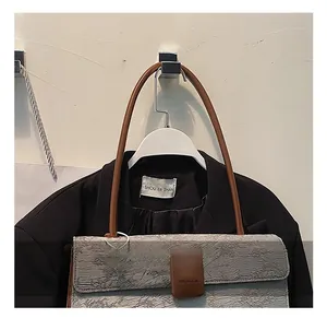 Détails de la texture plissée grise et bandoulière en cuir marron du sac baguette