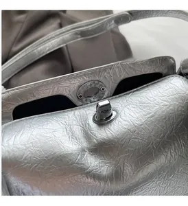 Detail of silver metallic handbag showing the textured finish and textured twist lock