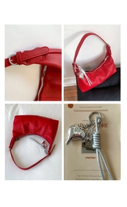 Detail of red hobo bag with litchi grain leather, silver heart charm and zip closure