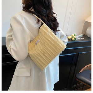 Detail of light yellow pleated canvas bucket bag with modern textured accordion fabric