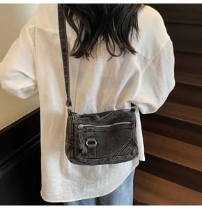 Detail of vintage denim crossbody bag featuring multiple metal zippers and pockets