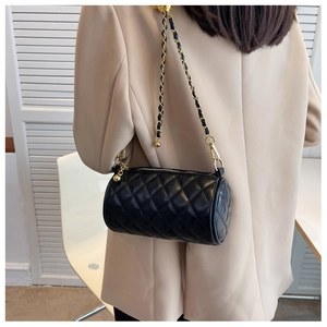 Détail du sac cylindrique matelassé noir avec bandoulière chaîne et breloque dorée