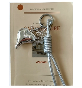 Close-up of silver heart and butterfly pendants on a woven cord over a vintage book