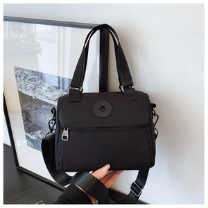 Close-up of black nylon square shoulder bag with brand logo and zipper detail