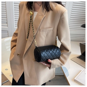 Détail du sac cylindrique noir matelassé avec chaîne dorée et réglage boule en métal