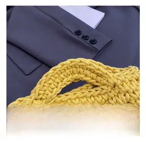 Detailed close-up of thick yellow knitted handle on a stylish woven bucket beach bag