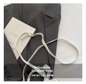Detail of adjustable white leather strap with silver metal buckle on a shoulder bag