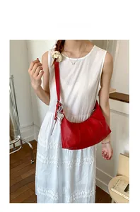 Detail of red crescent shoulder bag with litchi texture and silver butterfly charm
