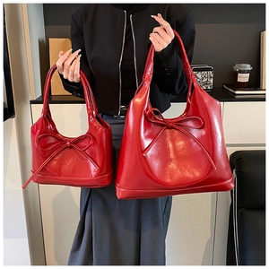 Detail showing two sizes of red oil wax leather tote bags with bow ribbon decoration
