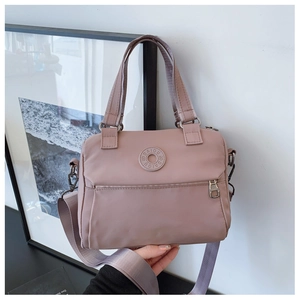 Detail of pink nylon shoulder bag showing top handles and adjustable webbing strap