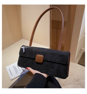Détail du tissu gaufré noir et de la bandoulière en cuir marron sur le sac baguette