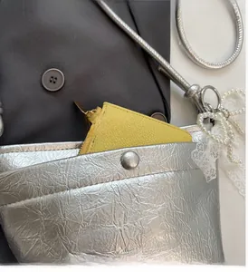 Detail of silver metallic bucket bag showing external pocket and brand logo embossing