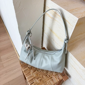 Detail of light blue crescent bag with silver heart charm and lychee leather texture
