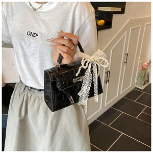 Close-up of black crocodile pattern Kelly bag with pearl lace bow and silver clasp