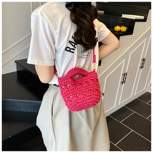 Detail of rose red woven bucket bag showing hollow texture and gold metal hardware