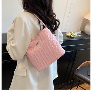 Detailed back view of pink pleated shoulder bag with brand label in cozy home setting