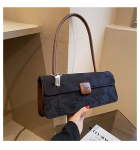 Détail d'un sac baguette en jacquard noir avec bandoulière en cuir marron et logo gravé