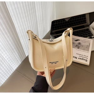 Detailed view of cream leather crossbody bag with silver twist lock and pebble texture