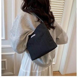 Detail of minimalist black pleated canvas tote bag with woven brand label on side