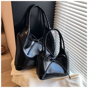 Two black oily leather tote bags with bows shown in different sizes under natural light