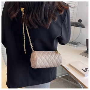 Détail d'un sac cylindrique matelassé beige avec bandoulière chaîne sur un mannequin