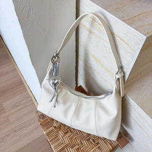 Close-up of cream lychee texture leather bag with heart pendant and silver zipper detail