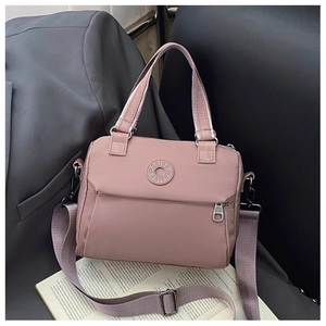 Detail of dusty pink nylon crossbody bag showing the woven strap and front zipper pocket