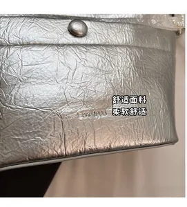 Detail of silver pleated bucket bag with metallic texture and magnetic snap closure